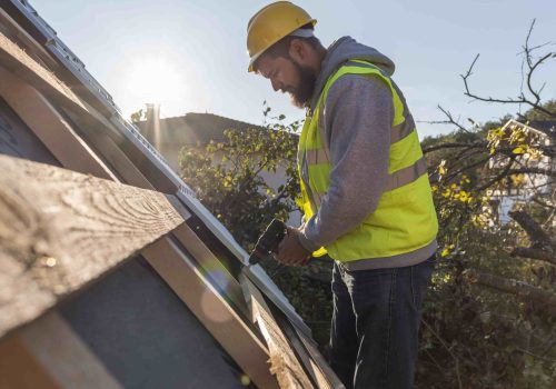 man working roof with drill min scaled